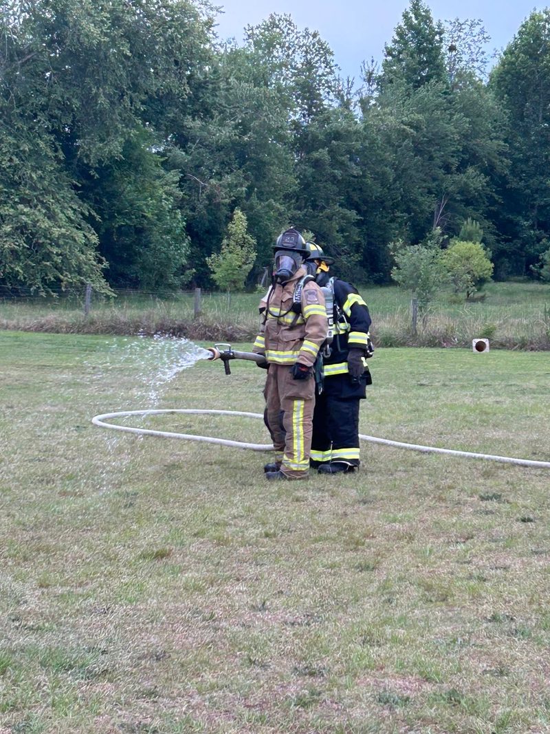 Two Crains Creek firefighters in air packs advance a hose line during training.
